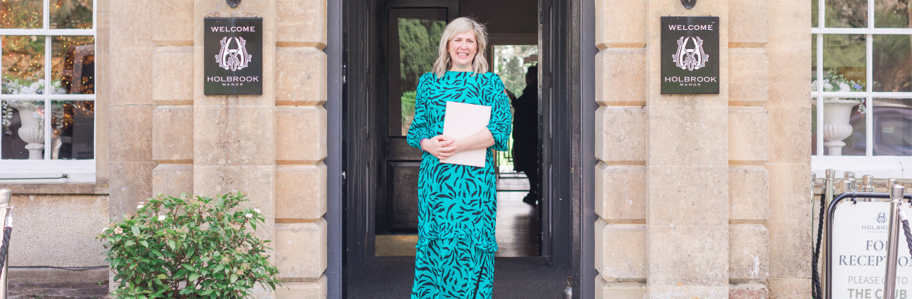 A woman stood in a archway in a green dress