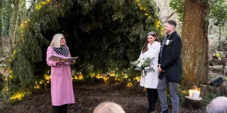 A woman marrying a man and woman in a woodland