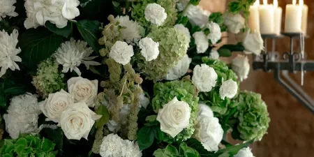 A close-up of a spray of white rose and other modern and elegant looking florals in the ceremony room at Ivy Lodge in Circencester.