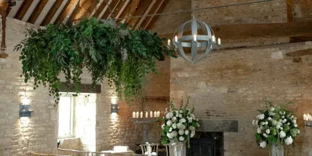 A shot of the ceremony room at Ivy Lodge in Cirencester. There are chairs laid out either side of the aisle and modern elegant wedding florals adorning the front of the ceremony space.