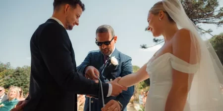 The groom's father places a cord over the couples hands in a handfasting ritual.