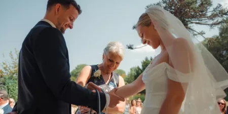 The bride's mother places a cord over the couples hands in a handfasting ritual.