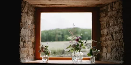 A photo of the view out of a window at Tockington Park wedding venue. There are some flowers in little vases on the window sill.