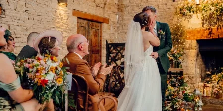 A photo of a bride and groom kissing at the end of their wedding ceremony.