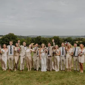Wedding guests stood in a field waving and smiling